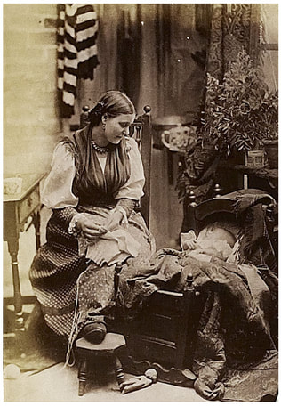 A photo from 1888 in black-and-white shows a mother sitting on a chair next to her baby in a wooden cradle. The mother is looking down into the sleeping child's face.